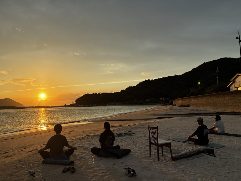 糸島・福の浦の浜辺で夕陽を眺めながらヨガを楽しむ参加者